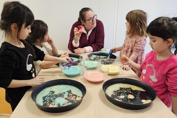Kinder an einem Tisch mit ihrer Erzieherin