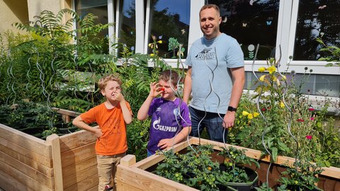 Stefan Beretz, Erzieher in der Kita Pusteblume, schaut mit Jakob und Noah nach den Tomaten.